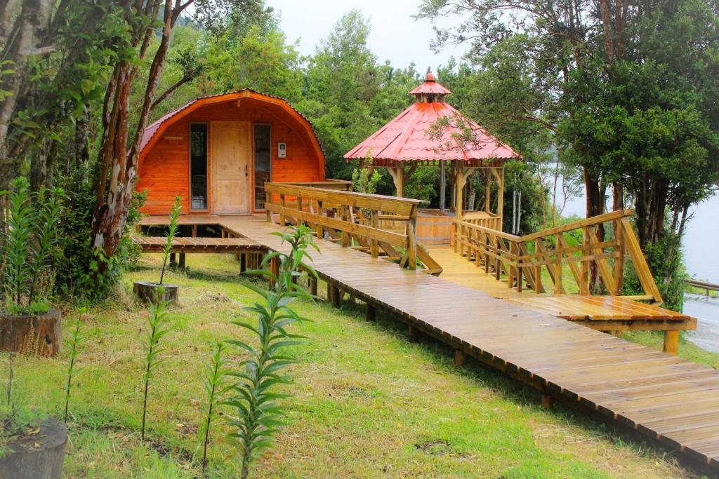 a wooden boardwalk leading to a gazebo on a lake at Eco Cabañas Wanderlust in Puerto Puyuhuapi