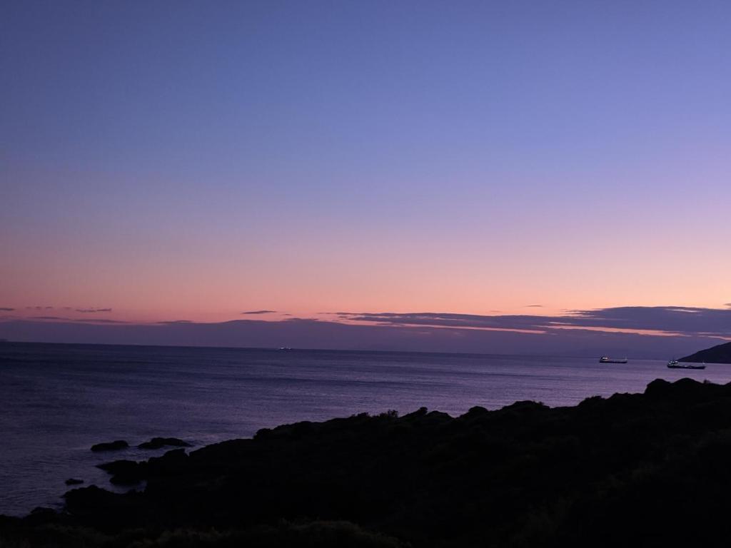 a sunset over the ocean with a boat in the distance at Green Coast in Sounio