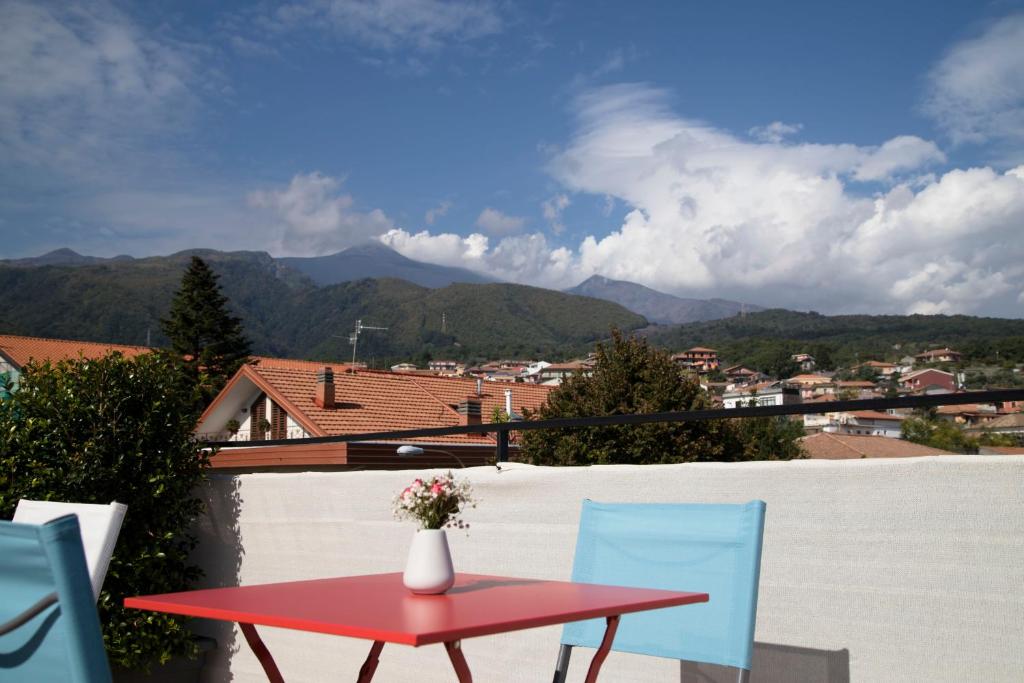 a red table and chairs on a balcony with mountains at Etna Sunrise b&b in Zafferana Etnea