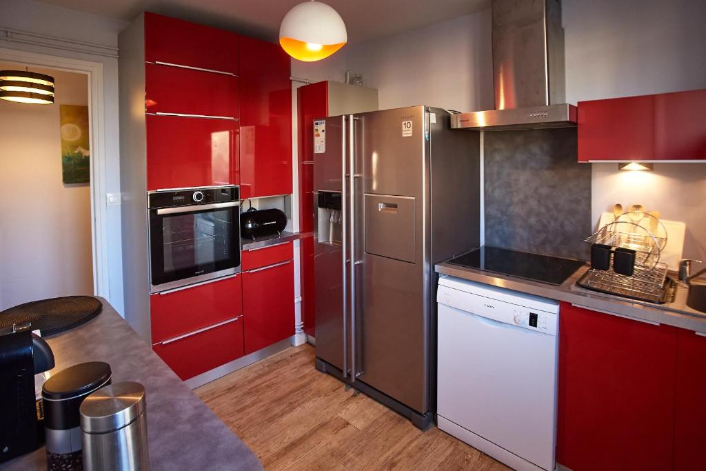La cuisine est équipée de placards rouges et d'un réfrigérateur en acier inoxydable. dans l'établissement Chambres à louer dans appartement Balcon - wifi - parking gratuit, à Nevers