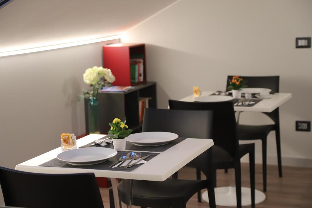 a table with black chairs and white plates on it at Etna Sunrise b&b in Zafferana Etnea