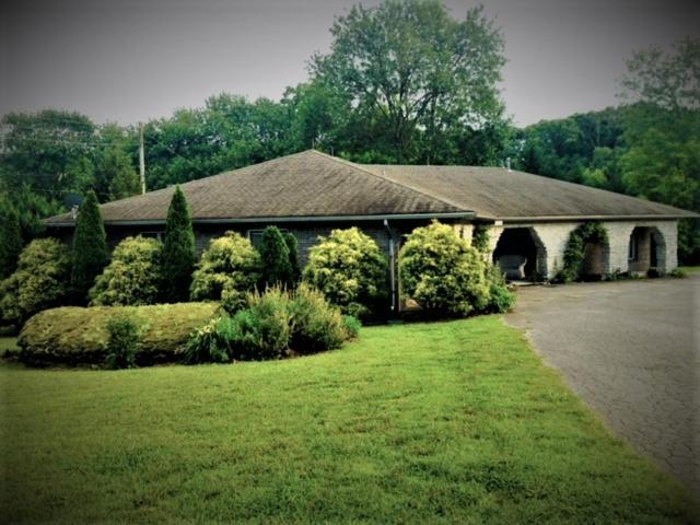 uma casa com um grande telhado num quintal verde em WINNIE'S BED & BREAKFAST em Lawrenceburg