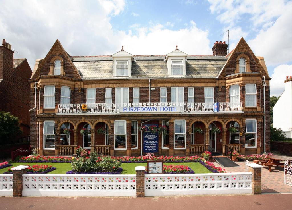 ein großes Backsteingebäude mit einem weißen Zaun davor in der Unterkunft Furzedown Hotel in Great Yarmouth