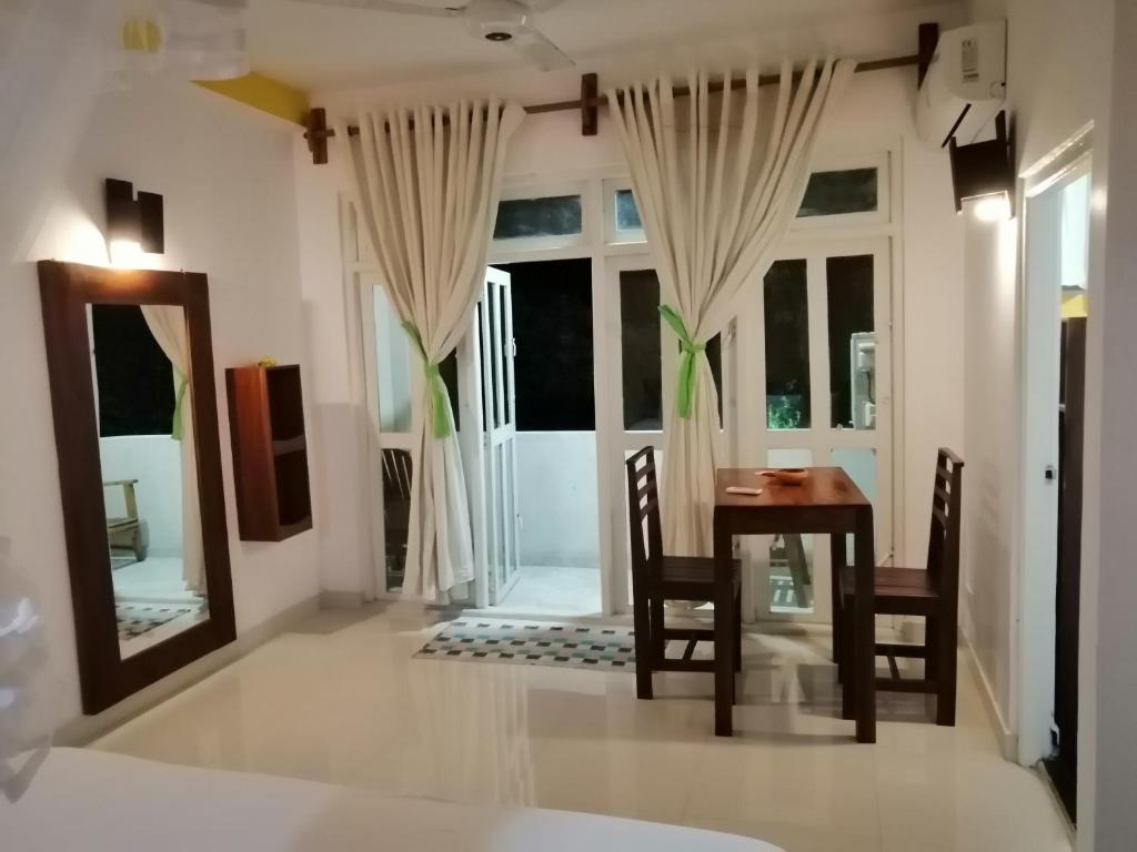 een eetkamer met een tafel en stoelen en een spiegel bij Sithila Villa in Mount Lavinia