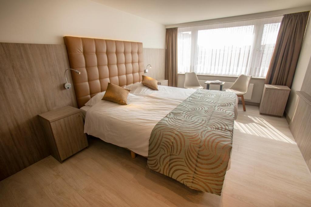 a bedroom with a large bed and a large window at Hotel Atlanta Knokke in Knokke-Heist