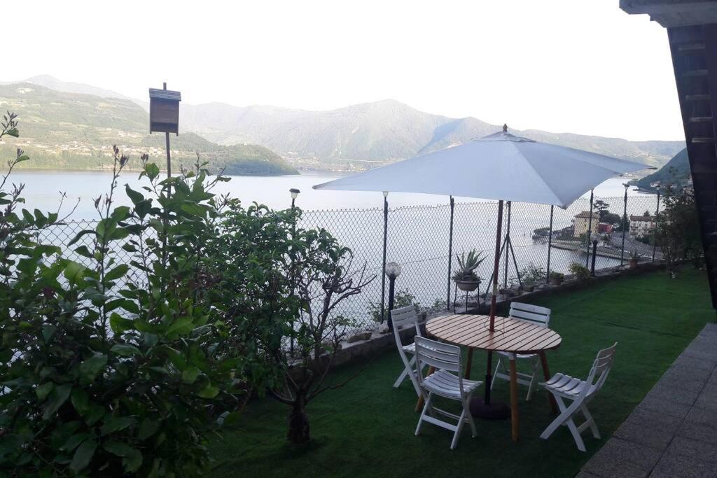 einen Tisch und Stühle mit einem Sonnenschirm und einem See in der Unterkunft Appartamento sul lago d'Iseo in Tavernola Bergamasca