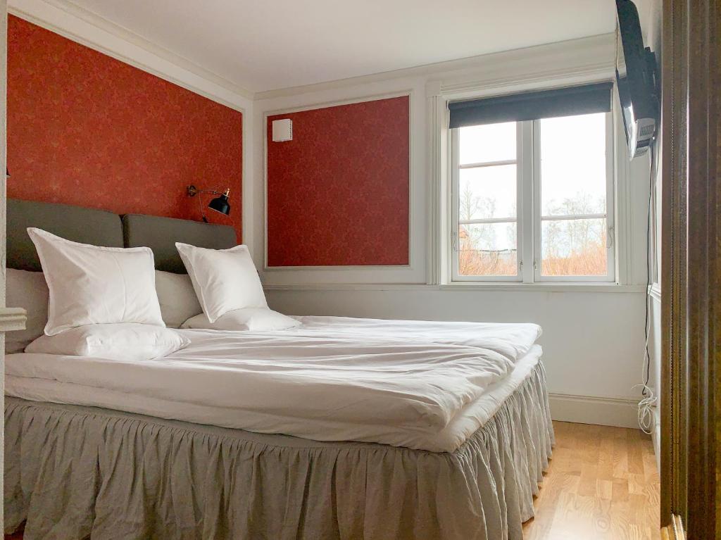 a bedroom with a large bed with a red wall at Mamma Carinas Pensionat B&B in Bankeryd