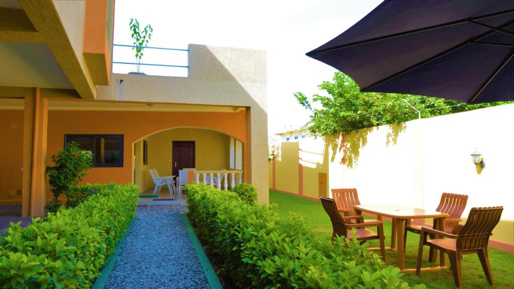 eine Terrasse mit einem Tisch, Stühlen und einem Sonnenschirm in der Unterkunft Villa Beach Avepozo Lome in Lomé