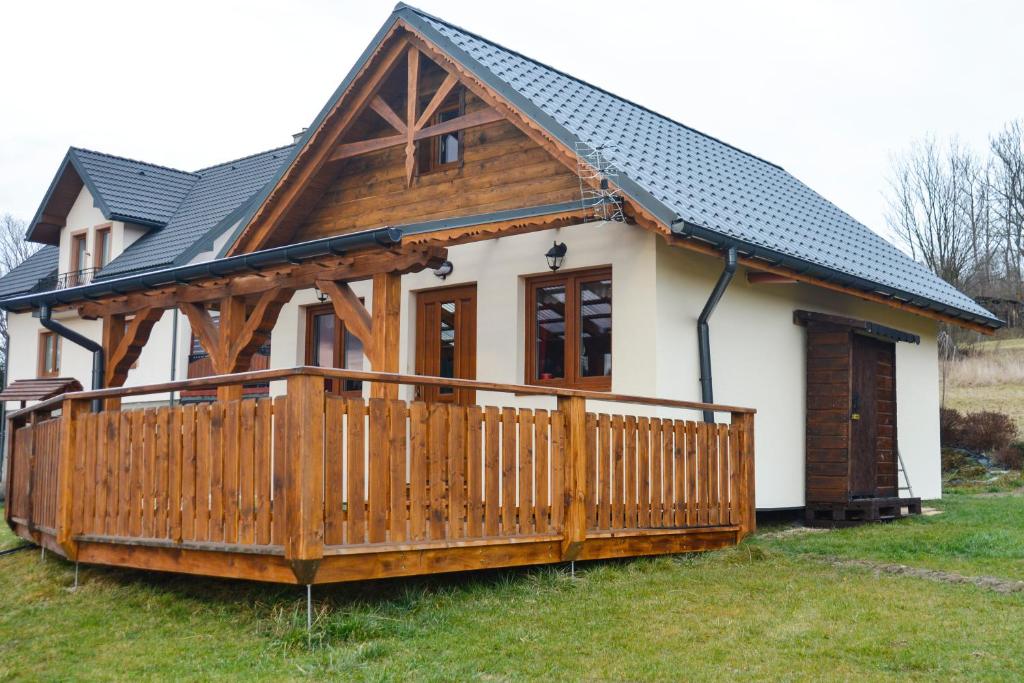 a small house with a large wooden deck at Domek Na Skarpie in Zubrzyca Dolna