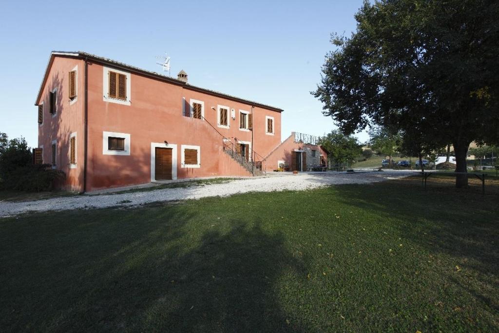 ein großes rotes Backsteingebäude mit einem Baum davor in der Unterkunft Godere Agricolo in Penna Alta