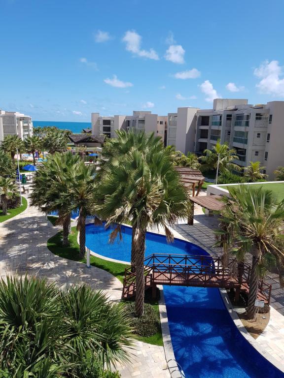 a view of a pool with palm trees and a bridge at Aquiraz Riviera Beach Place Golf Residence in Aquiraz