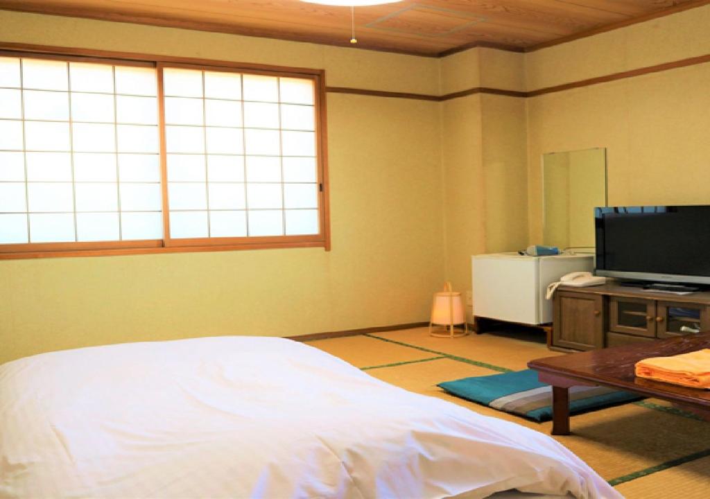 Bayside Hotel Ryugu / Vacation STAY 63718 في Anan: غرفة نوم بسرير وتلفزيون بشاشة مسطحة