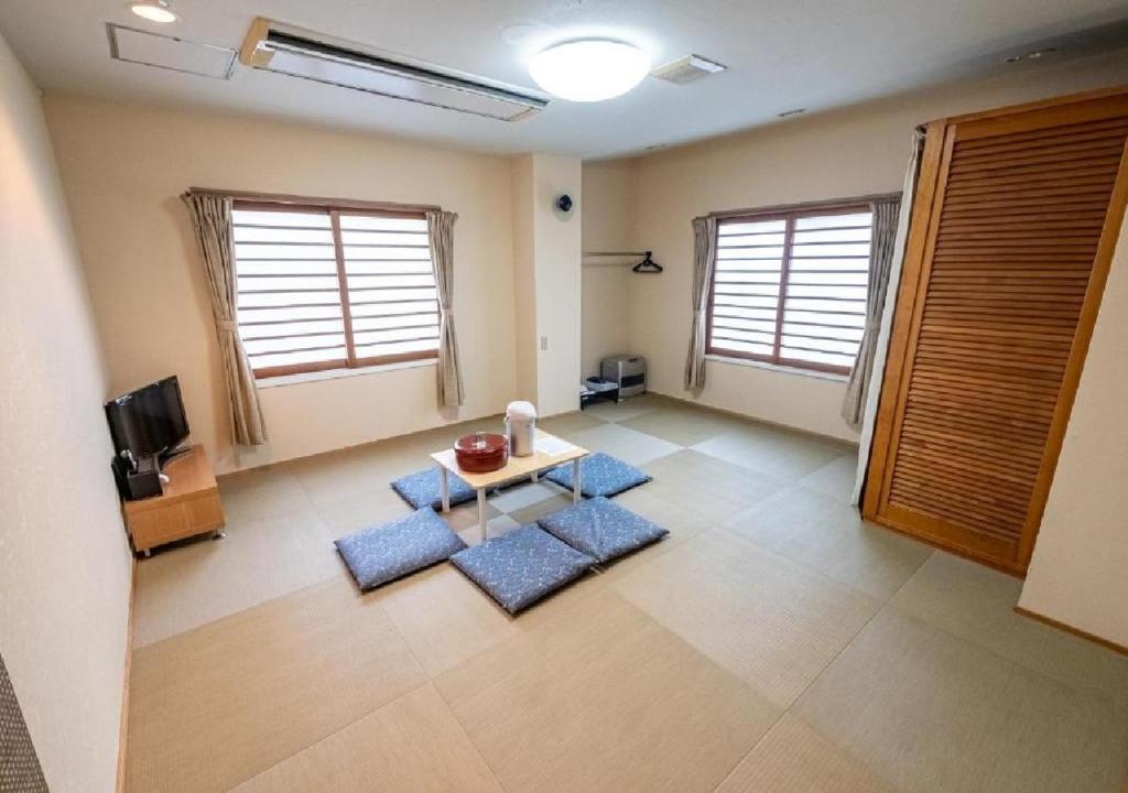 a living room with blue mats on the floor at kawagutiko station inn / Vacation STAY 63735 in Azagawa