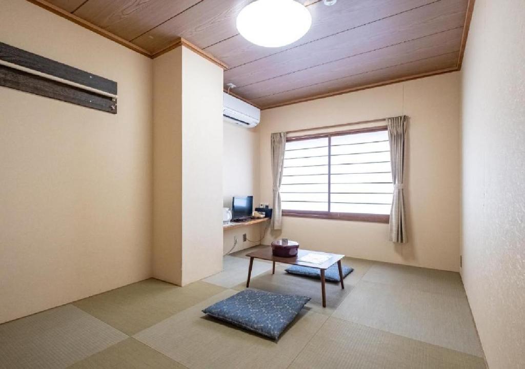 uma sala de estar com uma mesa e uma janela em kawagutiko station inn / Vacation STAY 63722 em Azagawa