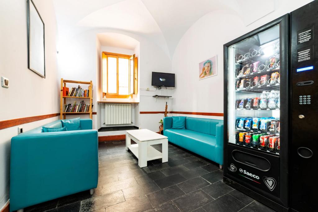 Habitación con sofás azules y nevera con latas de refresco. en Albergue las Veletas, en Cáceres