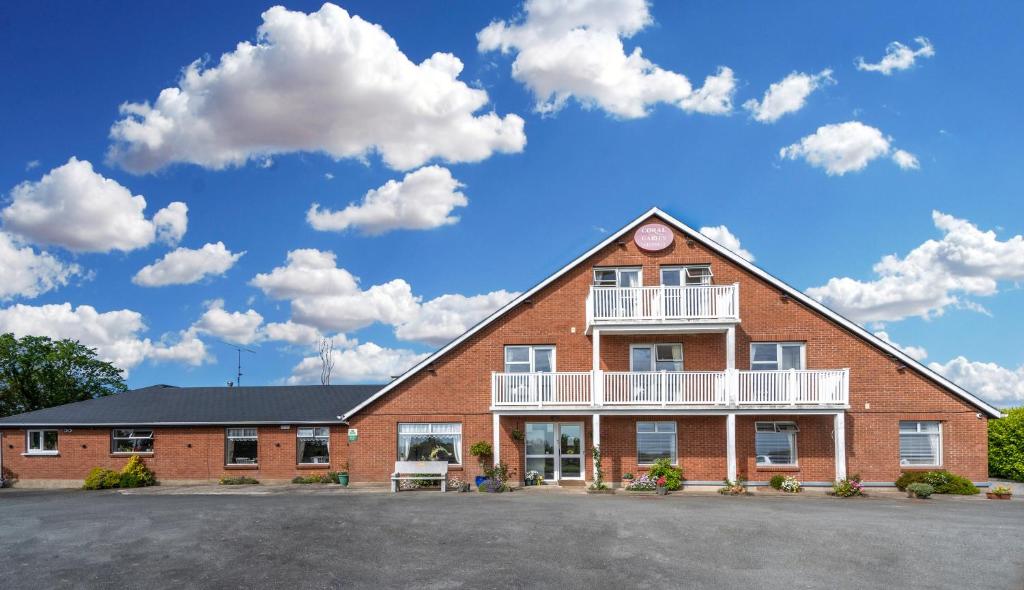 a large red brick building with a white balcony at Coral Gables Guesthouse & Campsite in Rosslare