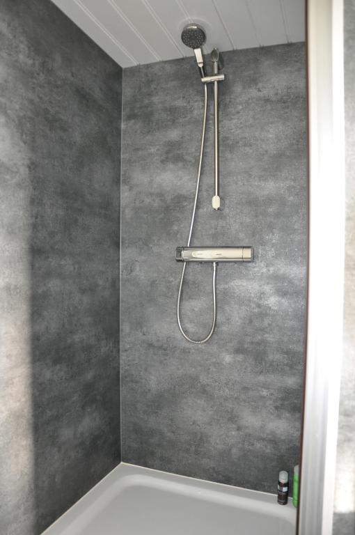 a shower in a bathroom with a gray wall at Private Lodge on Houseboat Amsterdam in Amsterdam