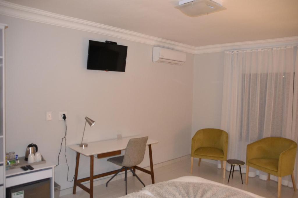 Pokój z biurkiem i krzesłami oraz telewizorem na ścianie w obiekcie Prisatt Boutique Hotel w mieście Onverwacht