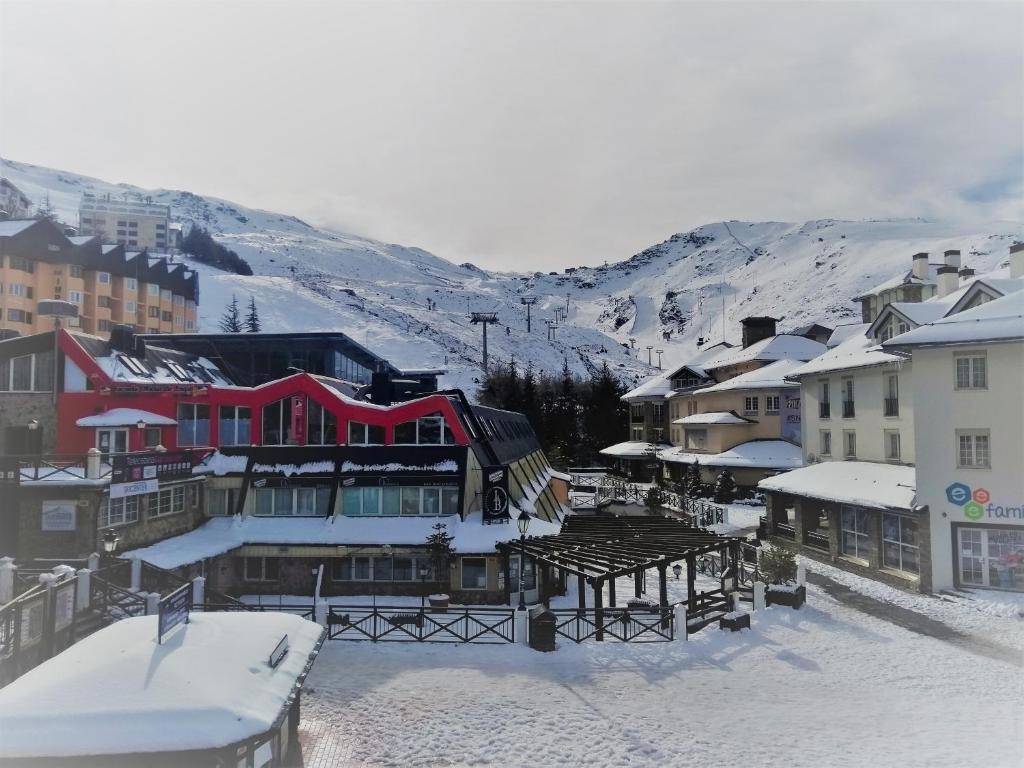 una ciudad cubierta de nieve con montañas en el fondo en TODOSIERRANEVADA ZONA BAJA - APARTAMENTOS DE 4 DORMITORIOS - Junto a los Telecabinas, en Sierra Nevada