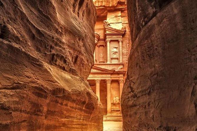 a building in the middle of a canyon between two rocks at The Red Rose City in Wadi Musa