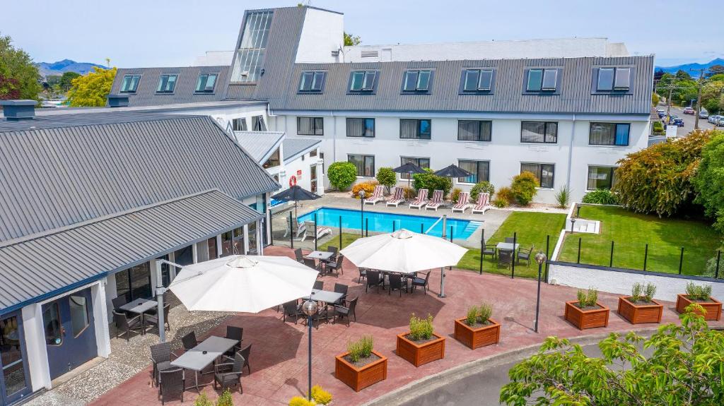 an outdoor patio with tables and umbrellas in front of a building at Scenic Hotel Marlborough in Blenheim