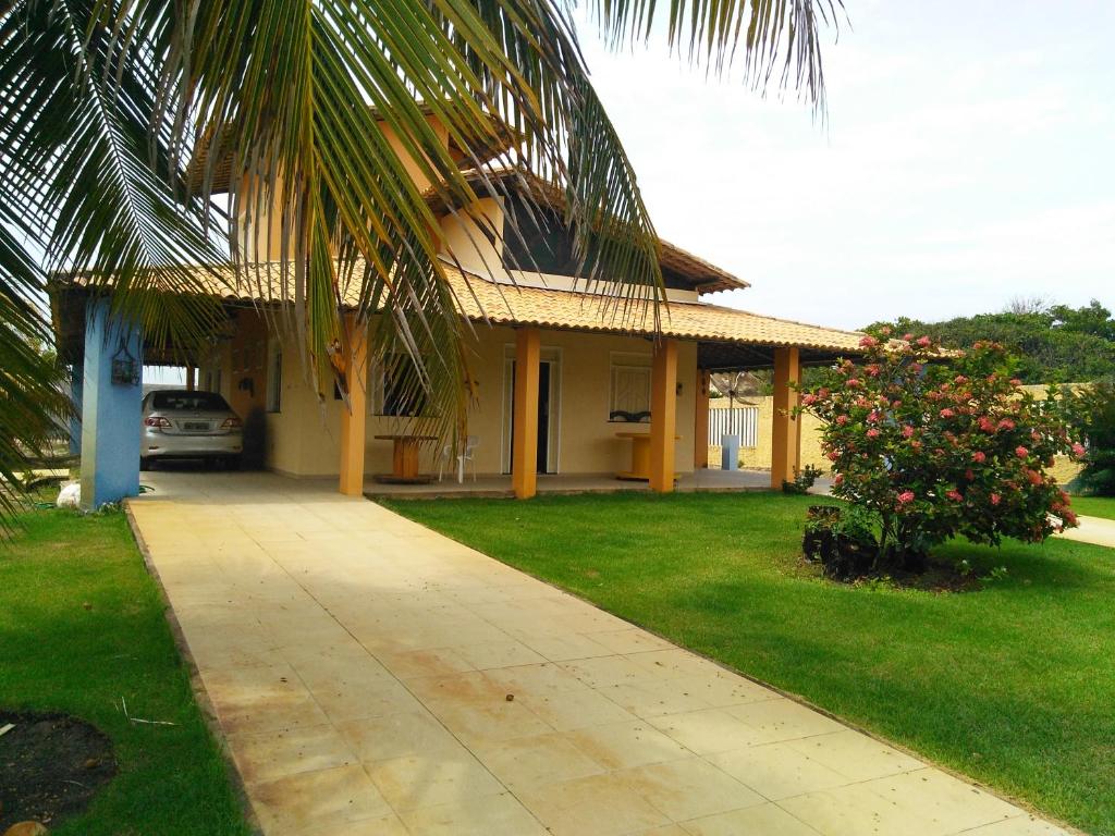 a house with a palm tree next to a driveway at Casa de praia condomínio fechado, frente para o mar in Estância