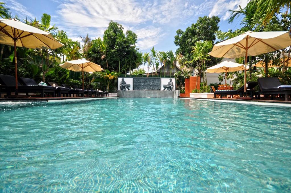 a swimming pool with chairs and umbrellas at The Sanctuary Residence in Siem Reap