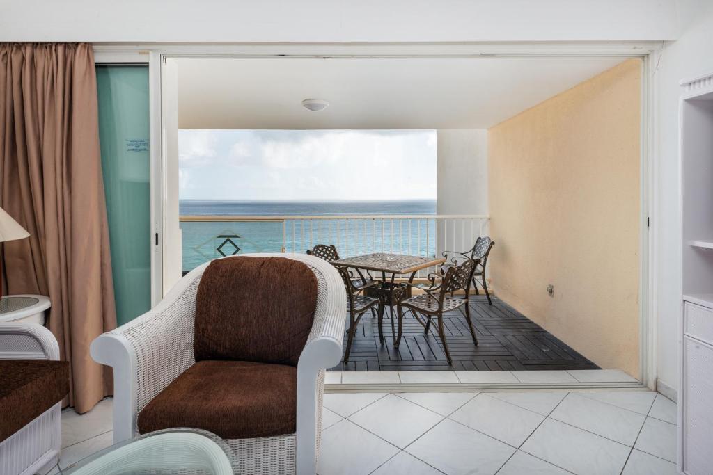 a room with a balcony with a table and chairs at Sint Maarten Blue Dream 1BR (C) in Cupecoy