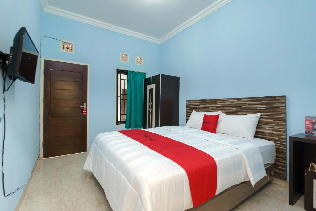 a bedroom with a large bed and a television at RedDoorz Syariah @ Mora Garden Bungo in Bebeko