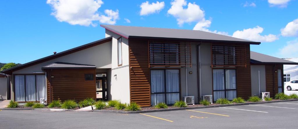 a brown and white building with a parking lot at Totara Lodge in Upper Hutt