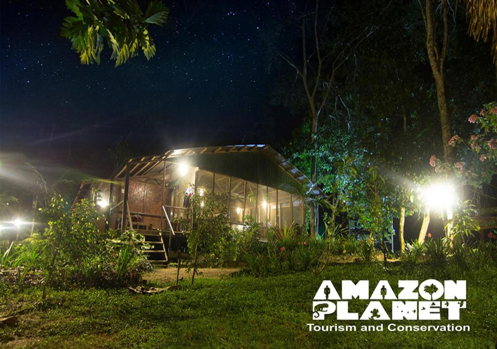 una casa por la noche con luces en el césped en Amazon Planet en Tambopata