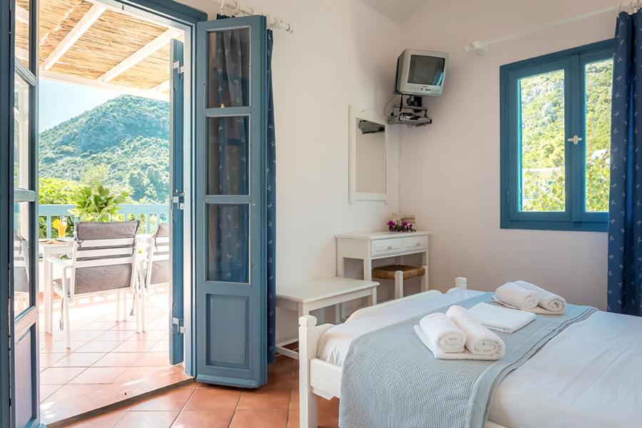 a bedroom with two beds and a sliding glass door at Limnonari Split Level Studio in Skopelos Town