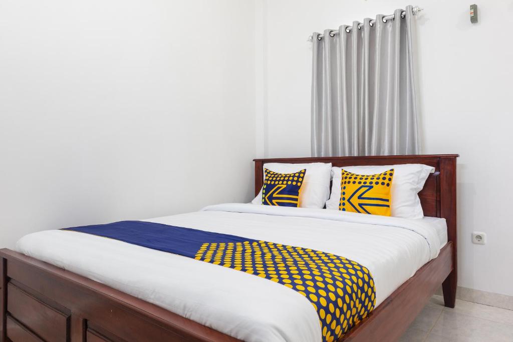 um quarto com uma cama com almofadas amarelas e azuis em SPOT ON 2063 Bethania Residence em Kupang