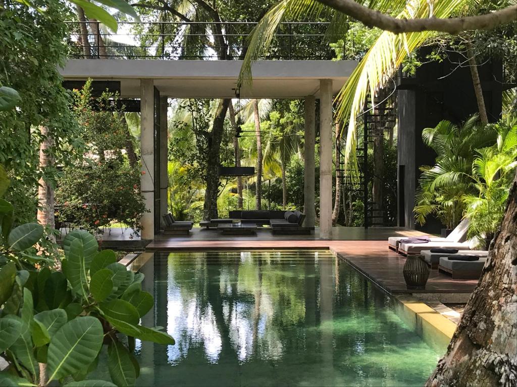 una piscina infinita en un jardín tropical con una casa en KAJU GREEN eco lodges en Unawatuna