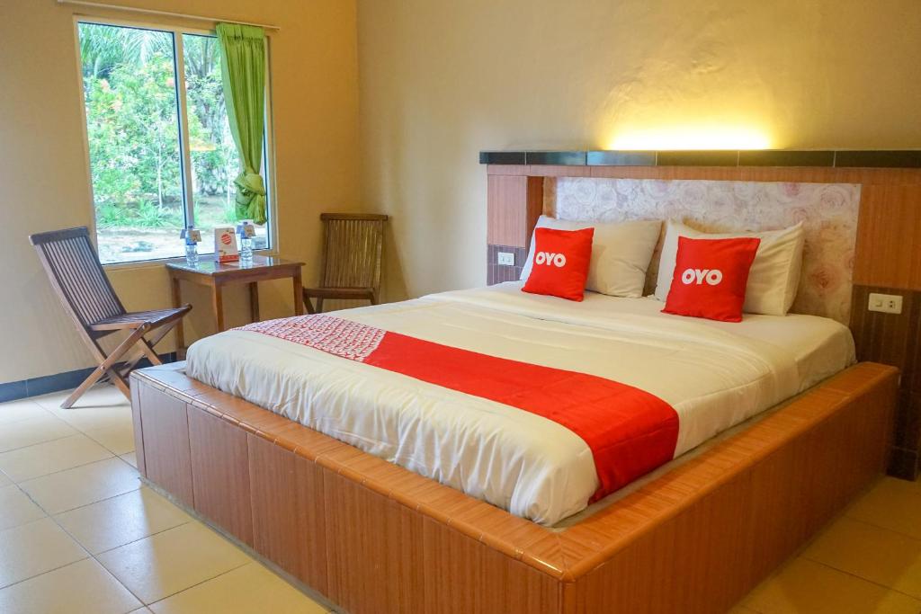 een slaapkamer met een groot bed met 2 rode kussens bij OYO 2029 Hotel Jatimas in Baturusa