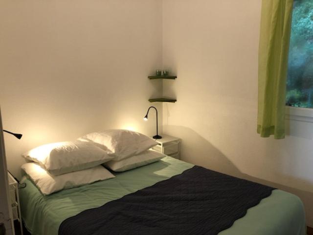 a bedroom with a bed with two pillows and a lamp at 50m Plage T2 Grande Terrasse Vue Mer Climatisé Piscine Chauffée, Parking clos gratuit in Sanary-sur-Mer