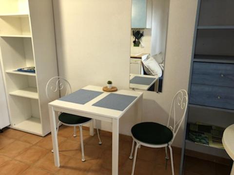 a small white table and two chairs in a room at 50m Plage T2 Grande Terrasse Vue Mer Climatisé Piscine Chauffée, Parking clos gratuit in Sanary-sur-Mer