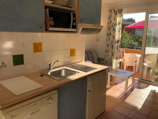 a kitchen with a sink and a view of a patio at 50m Plage T2 Grande Terrasse Vue Mer Climatisé Piscine Chauffée, Parking clos gratuit in Sanary-sur-Mer