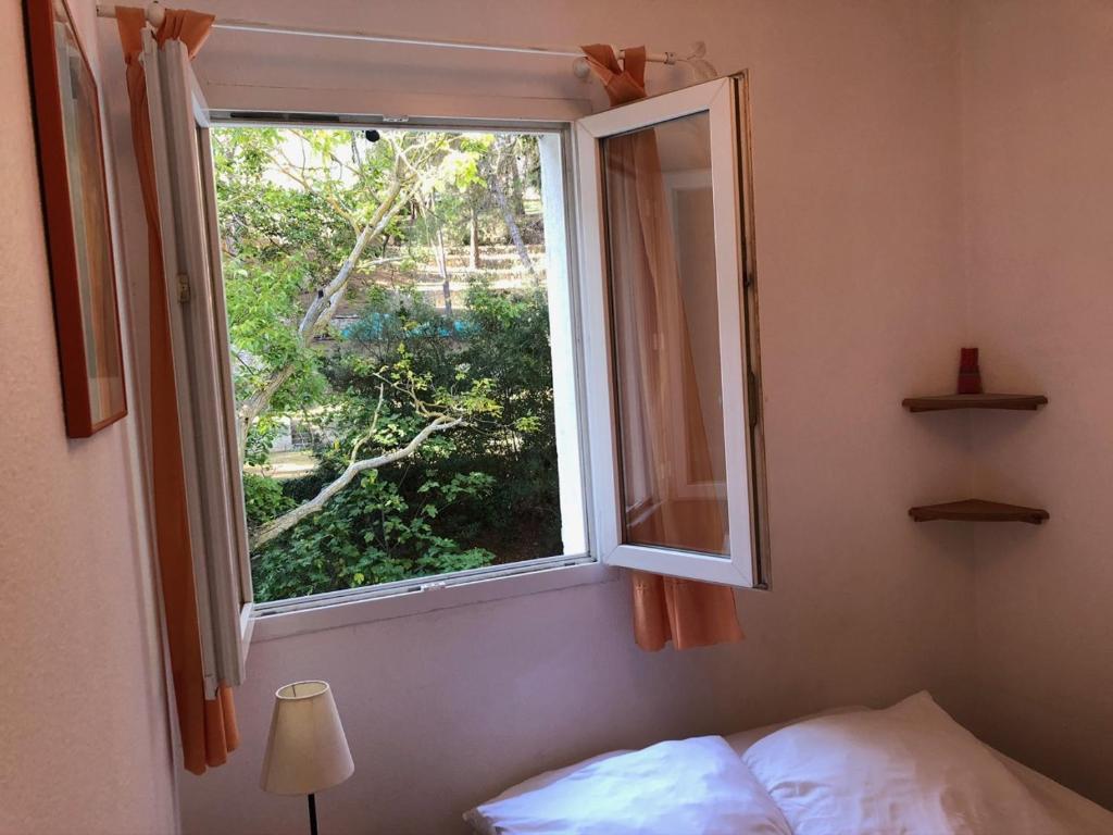 a bedroom with a window and a bed and a lamp at 50m Plage T2 Grande Terrasse Vue Mer Climatisé Piscine Chauffée, Parking clos gratuit in Sanary-sur-Mer