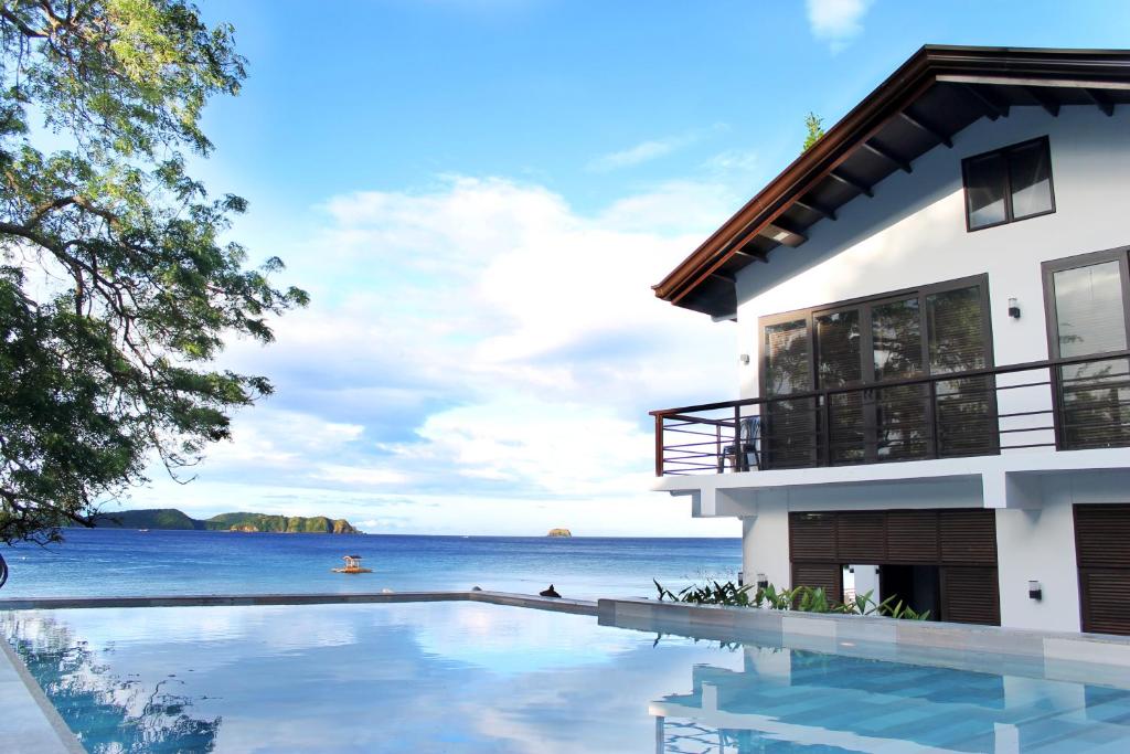 a house with a swimming pool in front of the ocean at Altamare Dive and Leisure Resort Anilao in Mabini