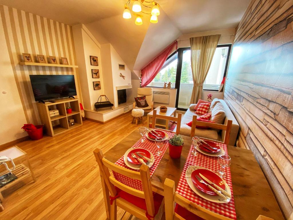 een woonkamer met een tafel en stoelen en een televisie bij Papa Moose Pamporovo in Pamporovo