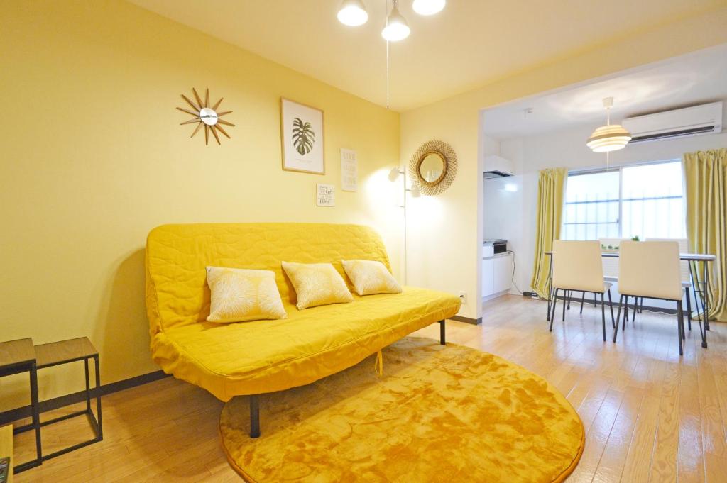 sala de estar con sofá amarillo y mesa en YUZU HOUSE, en Tokio