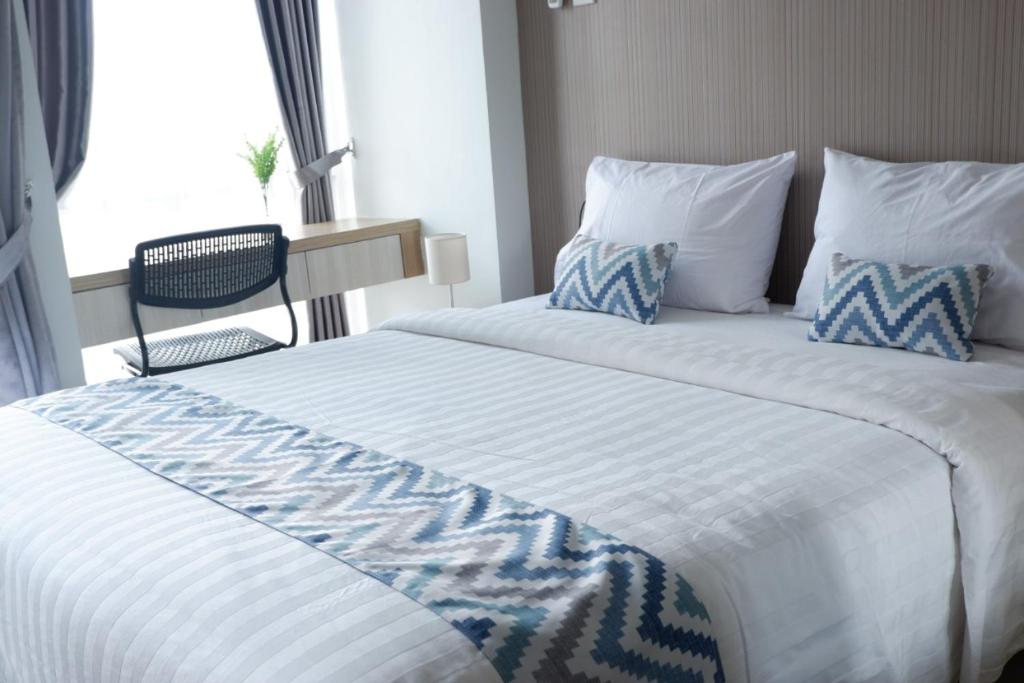 a large white bed with blue and white sheets and a window at Tiba at Jatinangor Hotel in Cikeruh