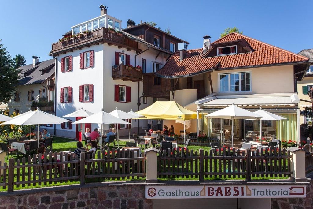 un edificio con mesas y sombrillas delante en Gasthaus Babsi en Soprabolzano