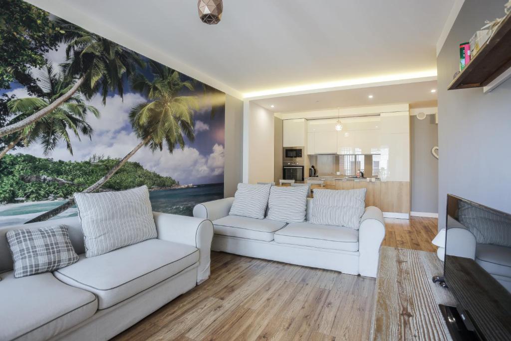 a living room with white couches and a painting of a beach at Apartament z balkonem Gdańsk Stare Miasto in Gdańsk