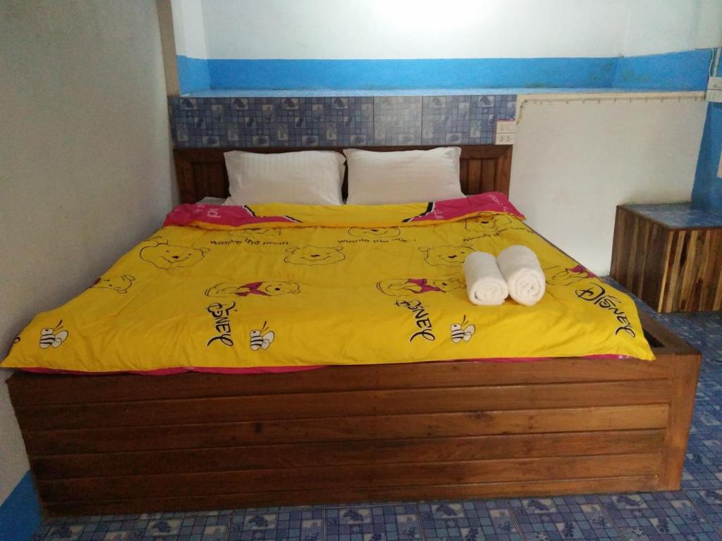 Una cama con sábanas amarillas y dos toallas. en ปฎิภาณบ้านพัก en Mae Hong Son
