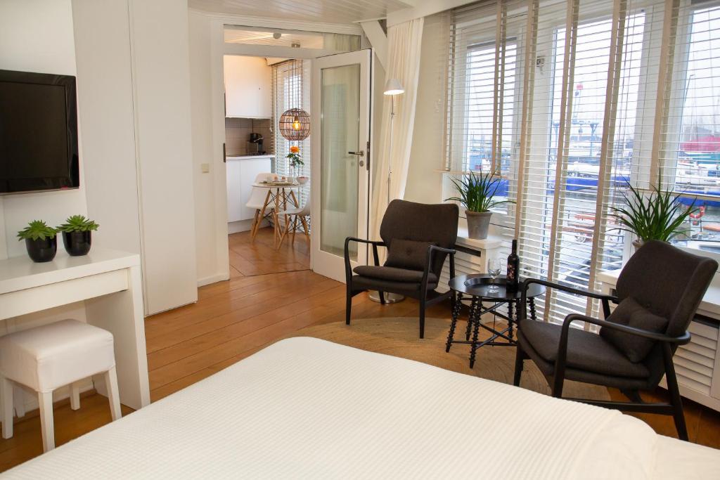 a bedroom with a bed and chairs and a living room at Apartments Waterland in Monnickendam