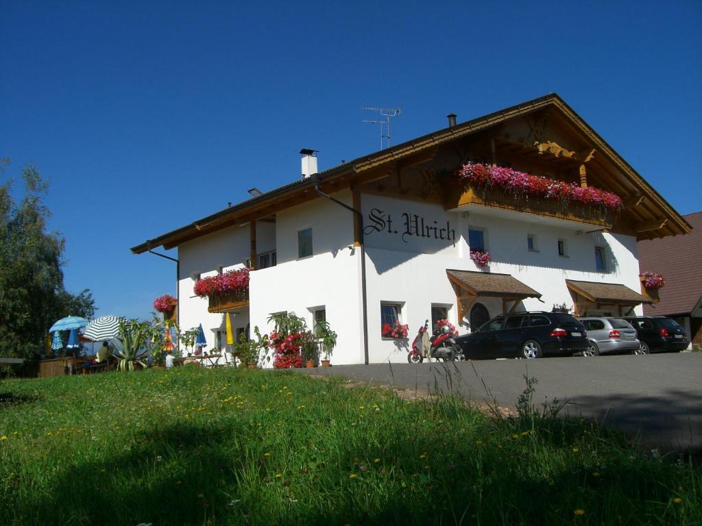 een wit gebouw met bloemen aan de zijkant bij Gasthof St. Ulrich in Meltina