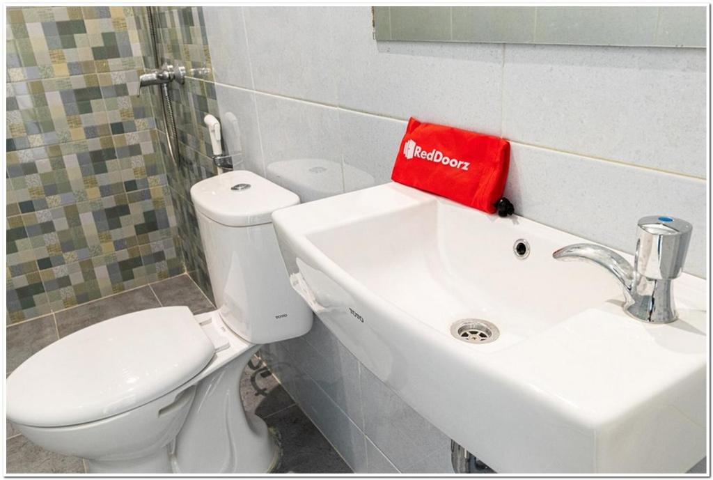 bagno con servizi igienici e una borsa rossa sul lavandino di RedDoorz Plus @ Centrium Katamso Medan a Medan