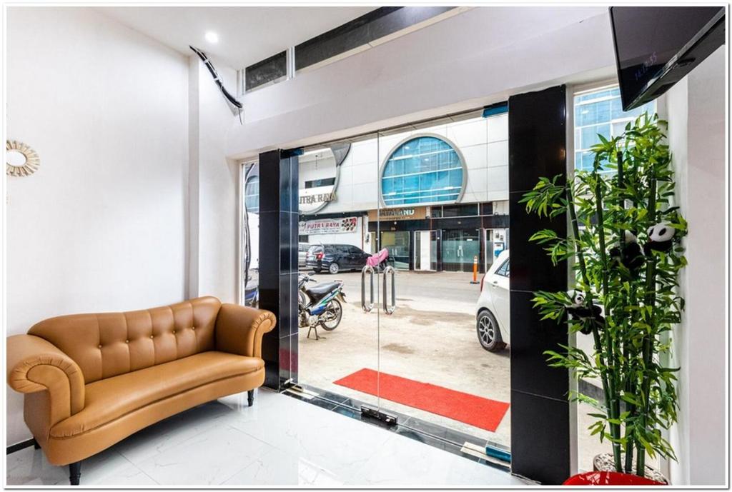 un soggiorno con divano e porta a vetri di RedDoorz Plus @ Centrium Katamso Medan a Medan